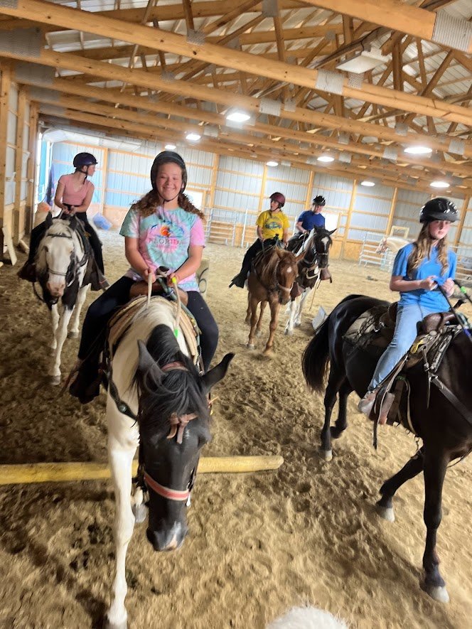 students riding horses around arena