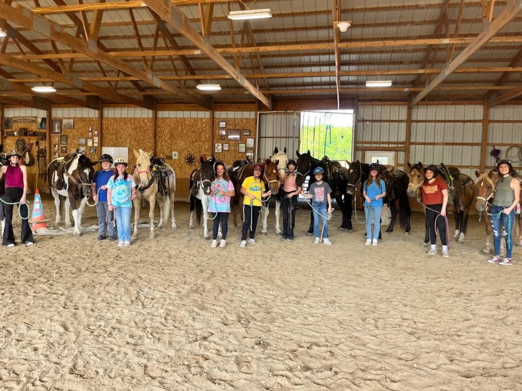 students stand with their horses smiling at camera