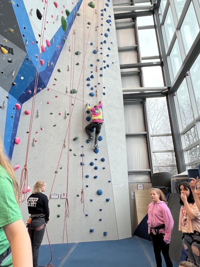 student scaling rock wall