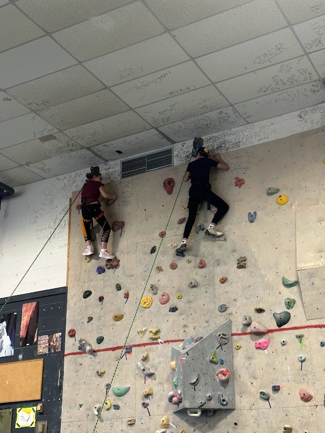 student reaches top of rock wall