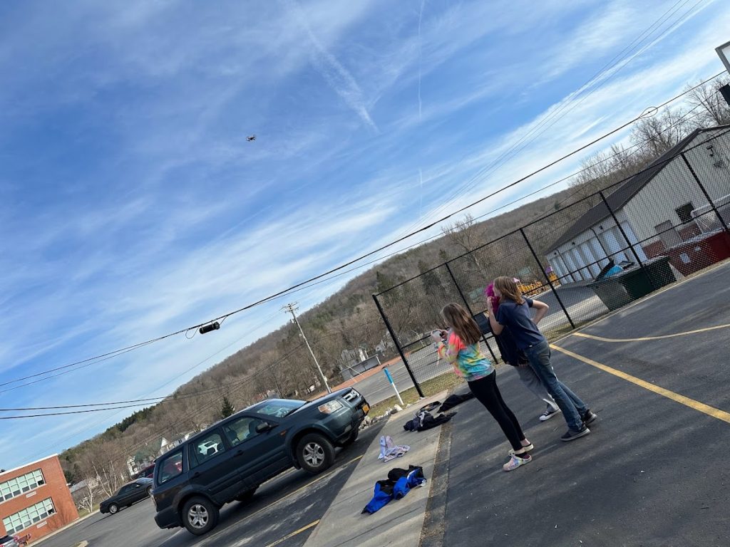 students fly drone in parking lot