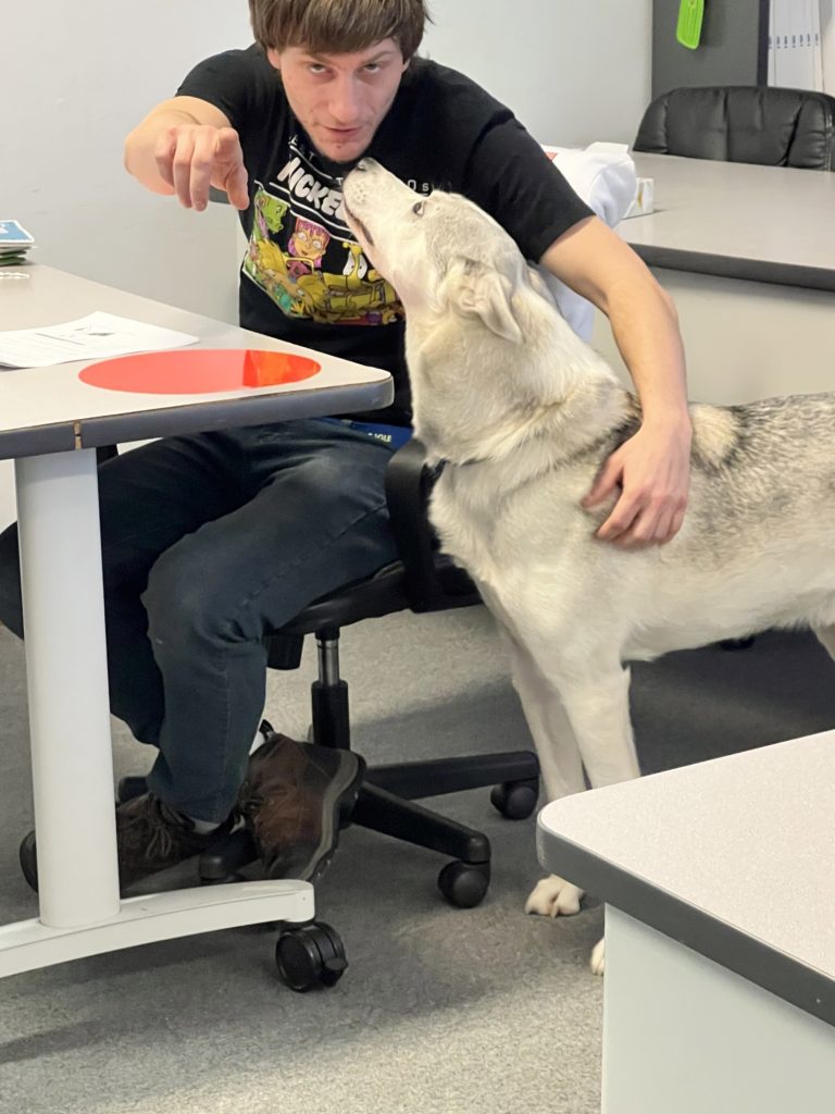 Student Alex points at camera with support animal