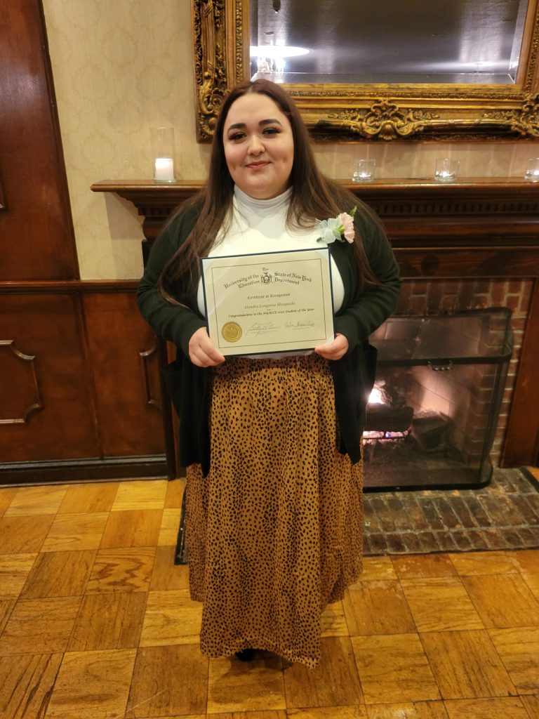 Alondra smiles at camera with Student of the Year certificate received in Albany