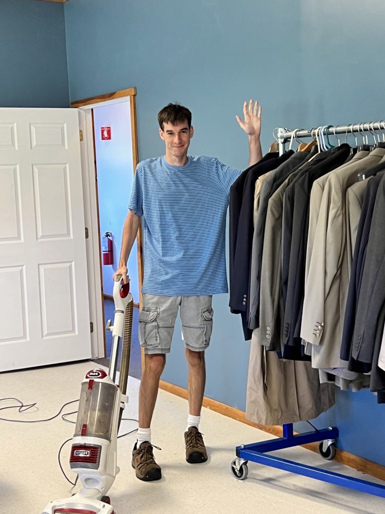 Student Donavan waves at camera while cleaning Career Impressions